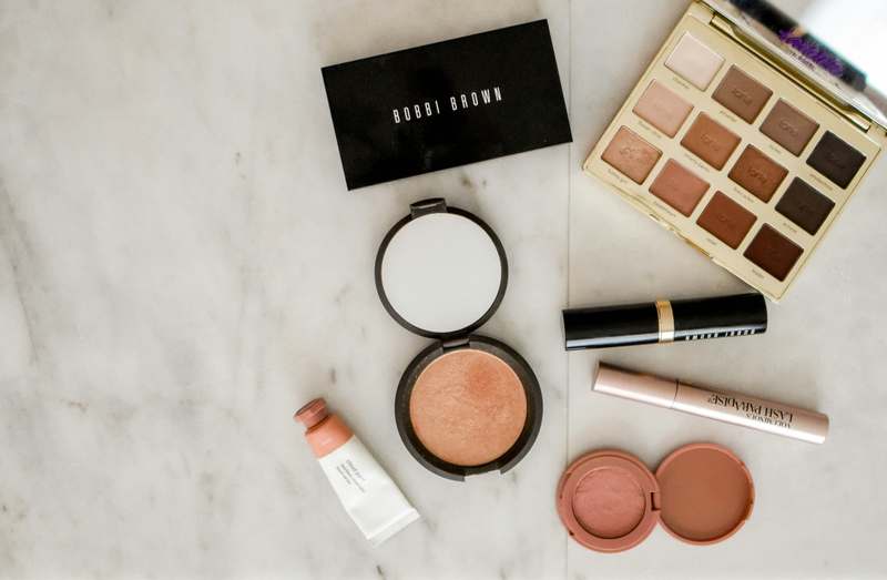 Grid layout of 12 different makeup sponges labeled with material type, density rating, and water absorption time, on a clean white marble surface